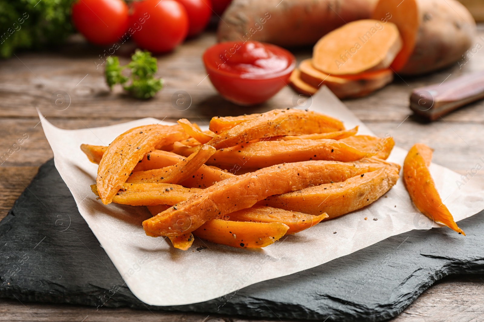 Photo of Slate board with sweet potato fries on table, closeup