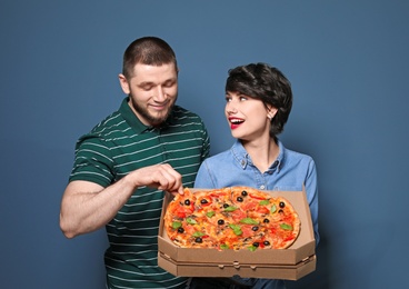 Photo of Attractive young couple with delicious pizza on color background