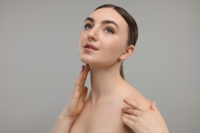 Photo of Beautiful woman touching her neck on grey background