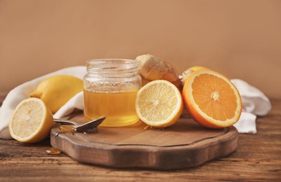 Photo of Citrus fruits, ginger and jar with honey on wooden table