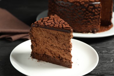 Photo of Piece of delicious chocolate truffle cake on black wooden table, closeup