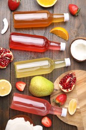 Photo of Delicious kombucha in glass bottles, fresh fruits and coconut on wooden table, flat lay