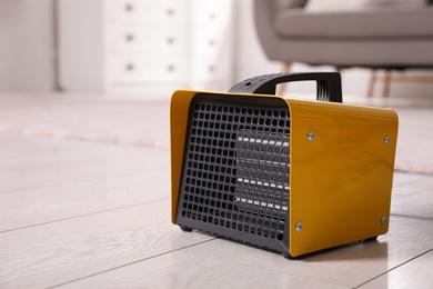 Photo of Modern electric heater on floor at home. Space for text