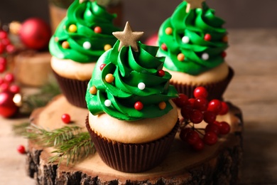 Photo of Christmas tree shaped cupcakes on wooden stand, closeup