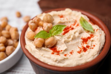 Photo of Delicious hummus with chickpeas and paprika served on white wooden table, closeup