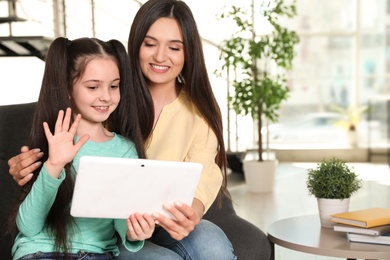 Photo of Mother and daughter using video chat on tablet at home