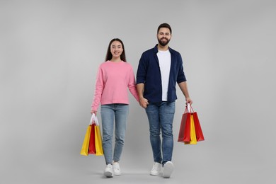 Photo of Happy couple with shopping bags on grey background