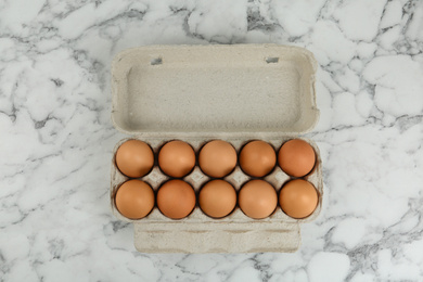 Photo of Raw chicken eggs on white marble table, top view