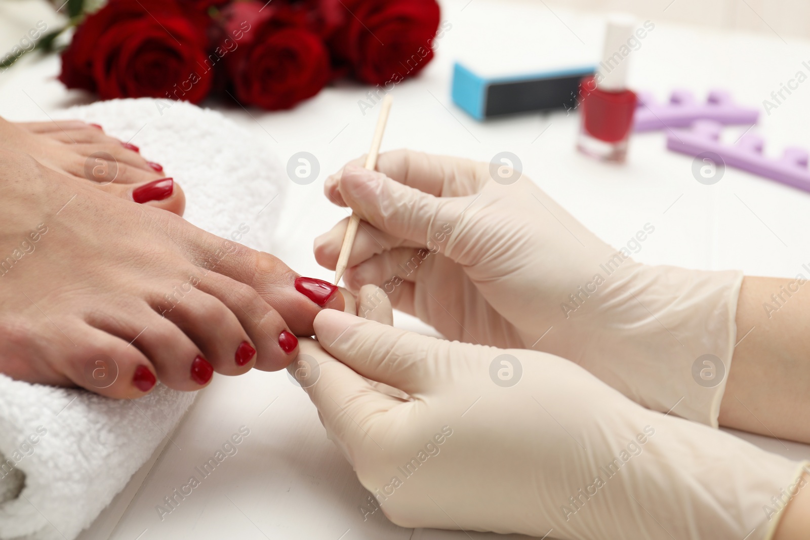 Photo of Pedicurist working with client`s toenails in beauty salon, closeup