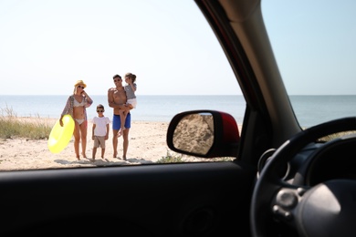 Photo of Happy family with inflatable ring at beach, view from inside of car