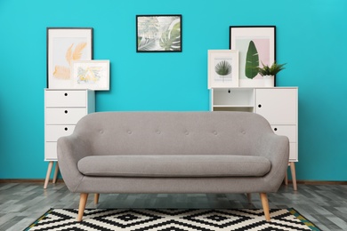 Photo of Modern interior of living room with comfortable gray sofa near color wall