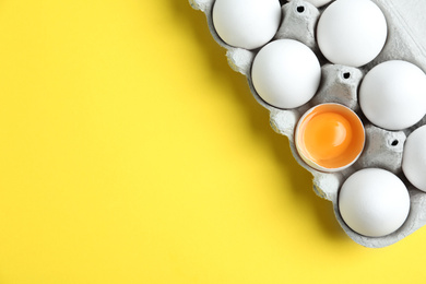 Photo of Fresh chicken eggs in box on yellow background, top view. Space for text