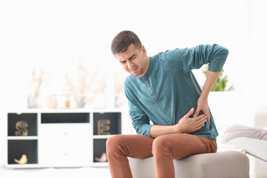 Photo of Young man suffering from pain in his side at home