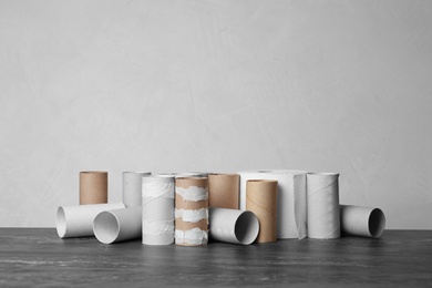 Photo of Full and empty toilet paper rolls on table against grey background. Space for text