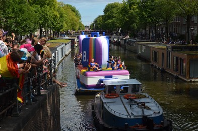 Photo of AMSTERDAM, NETHERLANDS - AUGUST 06, 2022: Many people in boats at LGBT pride parade on river
