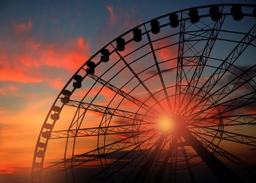 Image of Beautiful large Ferris wheel outdoors at sunset, low angle view