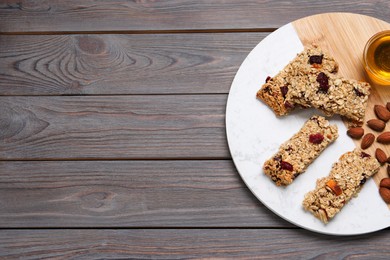 Photo of Tasty granola bars and ingredients on grey wooden table, top view. Space for text
