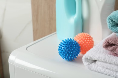 Photo of Dryer balls, stacked clean towels and detergents on washing machine