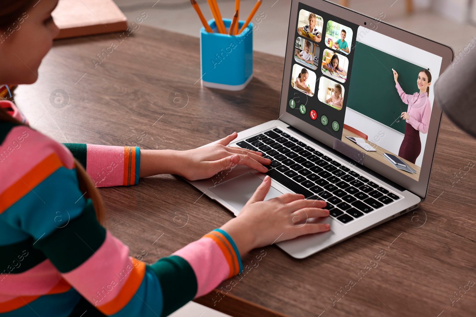 Image of E-learning. Little girl using laptop during online lesson at wooden table indoors, closeup