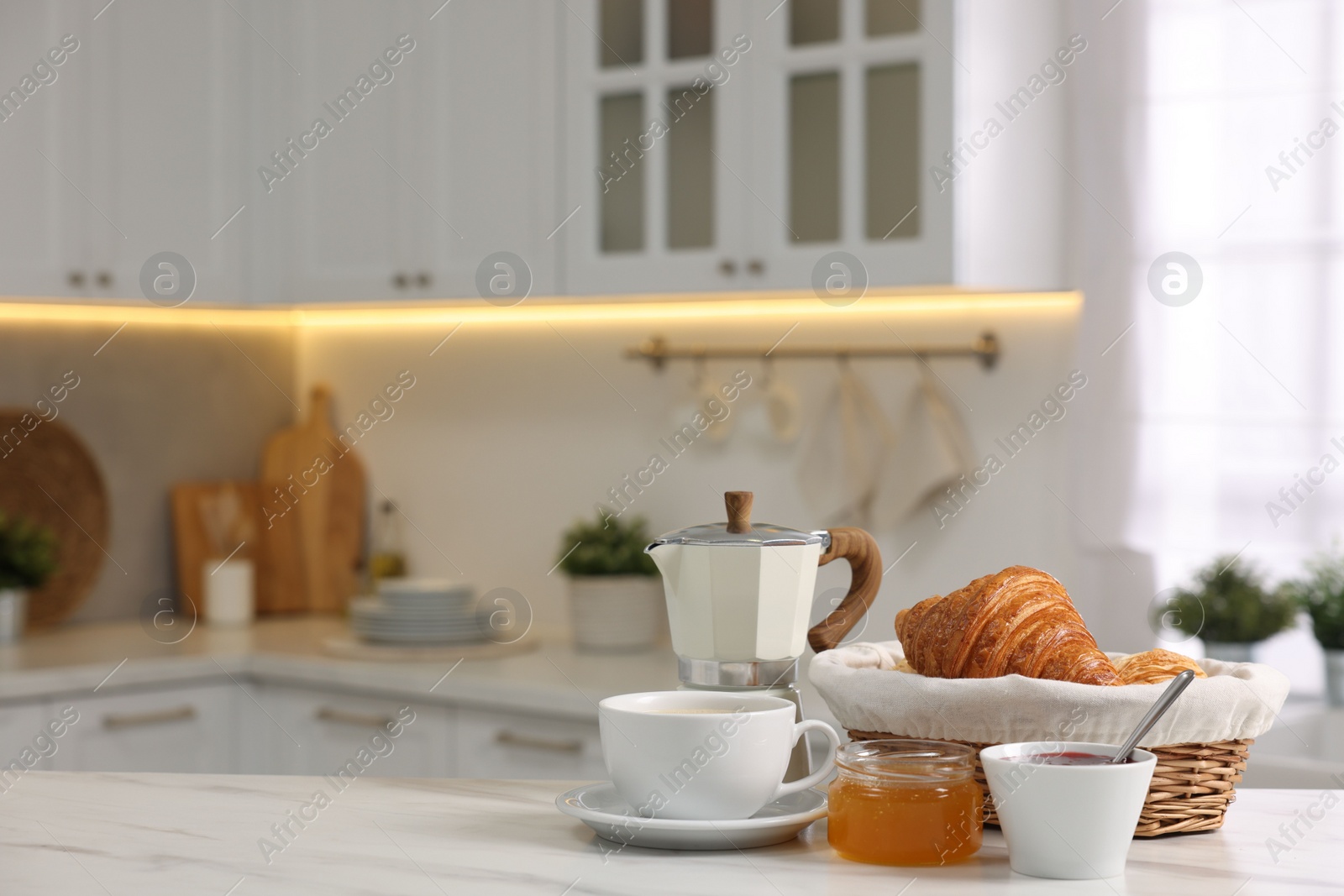 Photo of Breakfast served in kitchen. Fresh croissants, jam, honey and coffee on white table, space for text