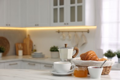 Photo of Breakfast served in kitchen. Fresh croissants, jam, honey and coffee on white table, space for text