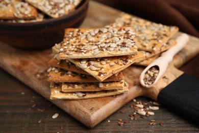 Photo of Cereal crackers with flax, sunflower and sesame seeds on wooden table, closeup