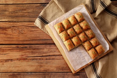Photo of Delicious sweet baklava on wooden table, top view. Space for text