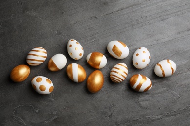 Photo of Flat lay composition of traditional Easter eggs decorated with golden paint on grey background