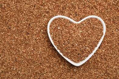 Photo of Heart shaped plate with buckwheat on grains, top view. Space for text