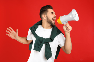 Photo of Young man with megaphone on red background
