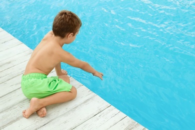 Photo of Little child near outdoor swimming pool. Dangerous situation