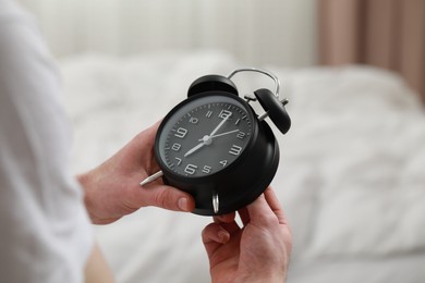 Photo of Man with alarm clock in bedroom, closeup of hands