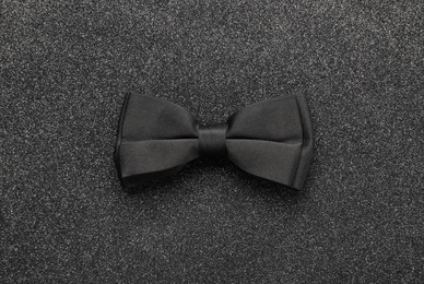 Photo of Stylish black bow tie on dark stone background, top view
