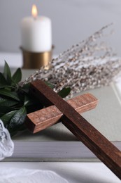 Photo of Book, cross and willow branches on white table, closeup