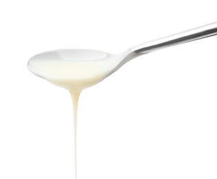 Photo of Pouring condensed milk from metal spoon isolated on white