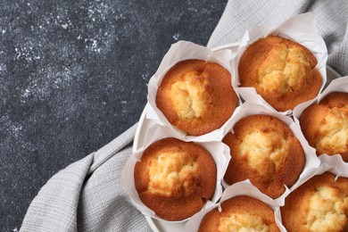 Photo of Delicious sweet muffins on black textured table, top view. Space for text