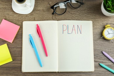 Photo of Notebook with word Plan, coffee, alarm clock, eyeglasses and stationery on wooden table, flat lay