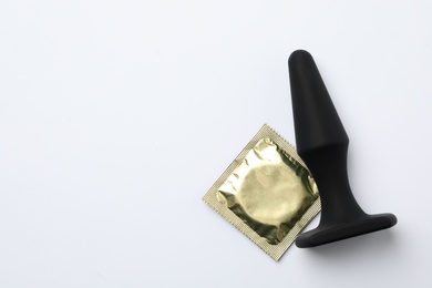 Photo of Anal plug and condom on white background, top view. Sex game