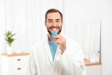 Photo of Young man using teeth whitening device at home