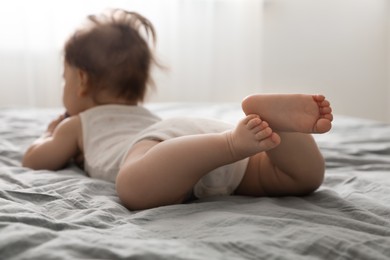 Photo of Little baby lying on bed indoors, focus on legs
