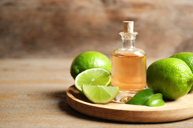 Photo of Lime essential oil and citrus fruits on wooden table