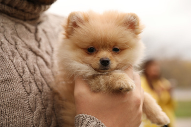 Photo of Man with small fluffy dog outdoors on autumn day, closeup