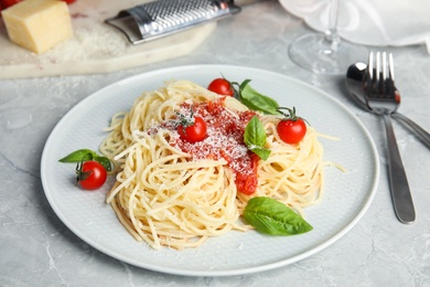 Photo of Tasty pasta with tomatoes, cheese and basil on light grey marble table