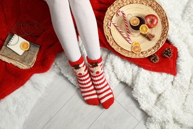 Photo of Woman and cup of hot winter drink on floor at home, top view
