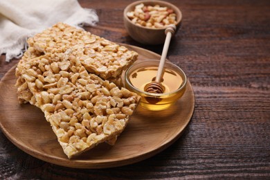 Photo of Delicious peanut bars (kozinaki) and ingredients on wooden table. Space for text