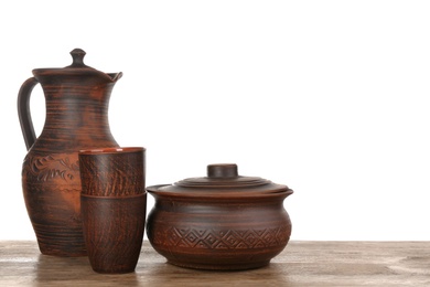 Photo of Set of clay dishes on wooden table against white background