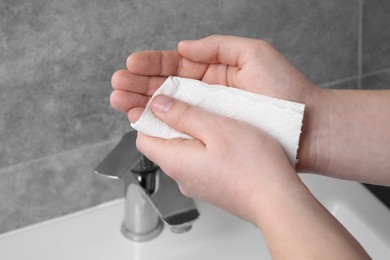 Photo of Woman wiping hands with paper towel in bathroom, closeup