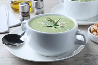 Photo of Delicious asparagus soup with green onion served on white wooden table, closeup