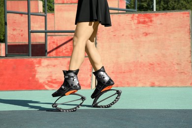 Photo of Woman doing exercises in kangoo jumping boots in workout park, closeup