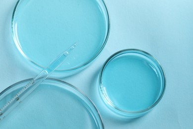 Photo of Measuring pipette and petri dishes on light blue table, flat lay